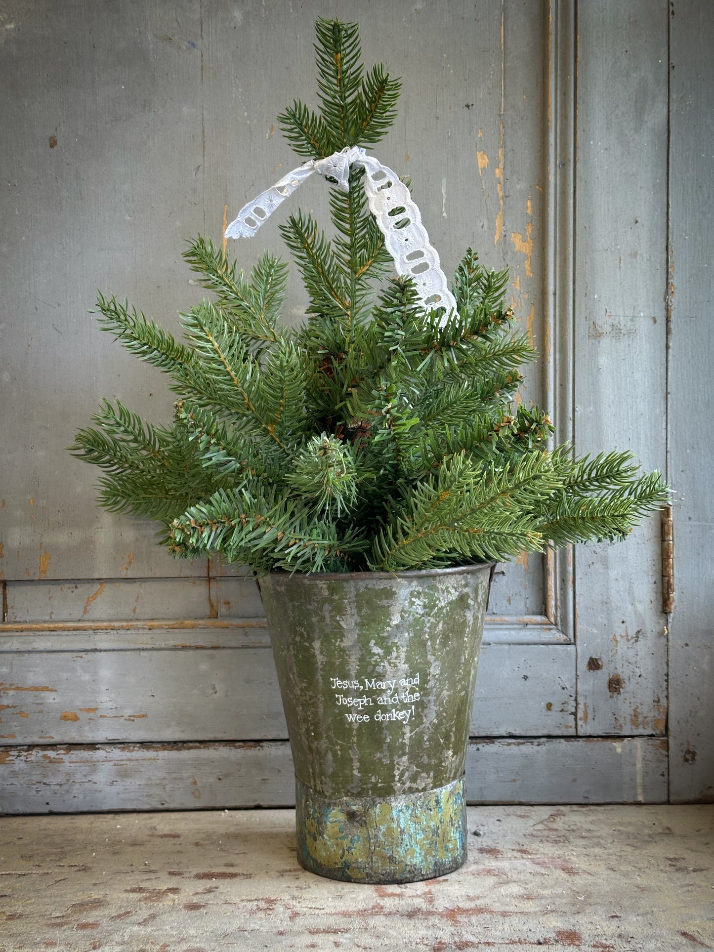 A Recycled Metal Mini Christmas Tree Bucket With A Hand Painted Quote