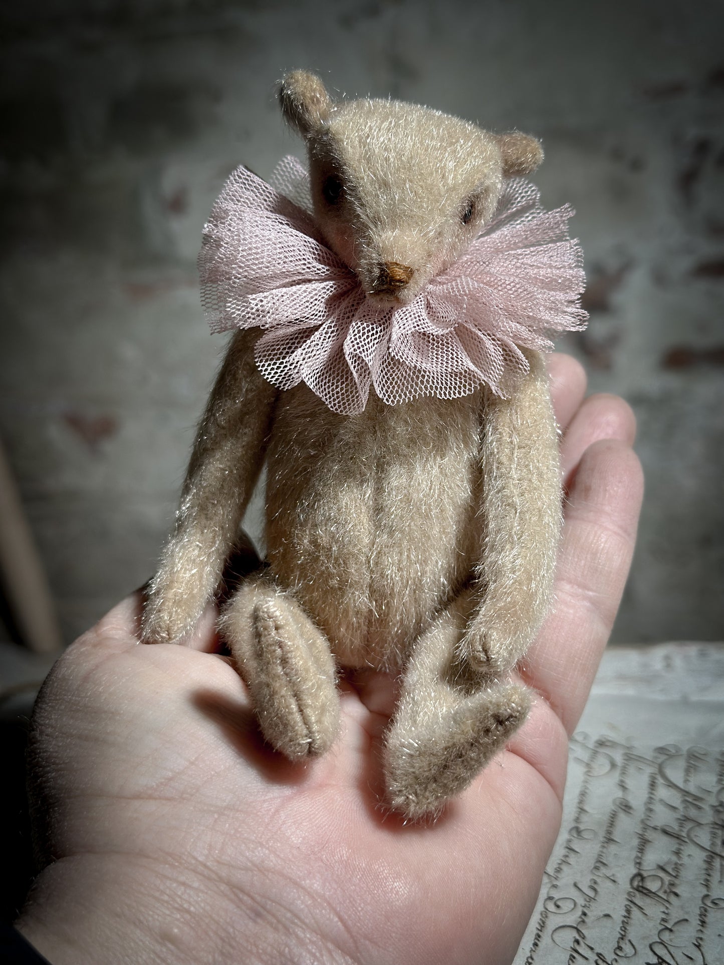 A beautiful hand made jointed collector’s teddy bear with antique pink tulle ruffle