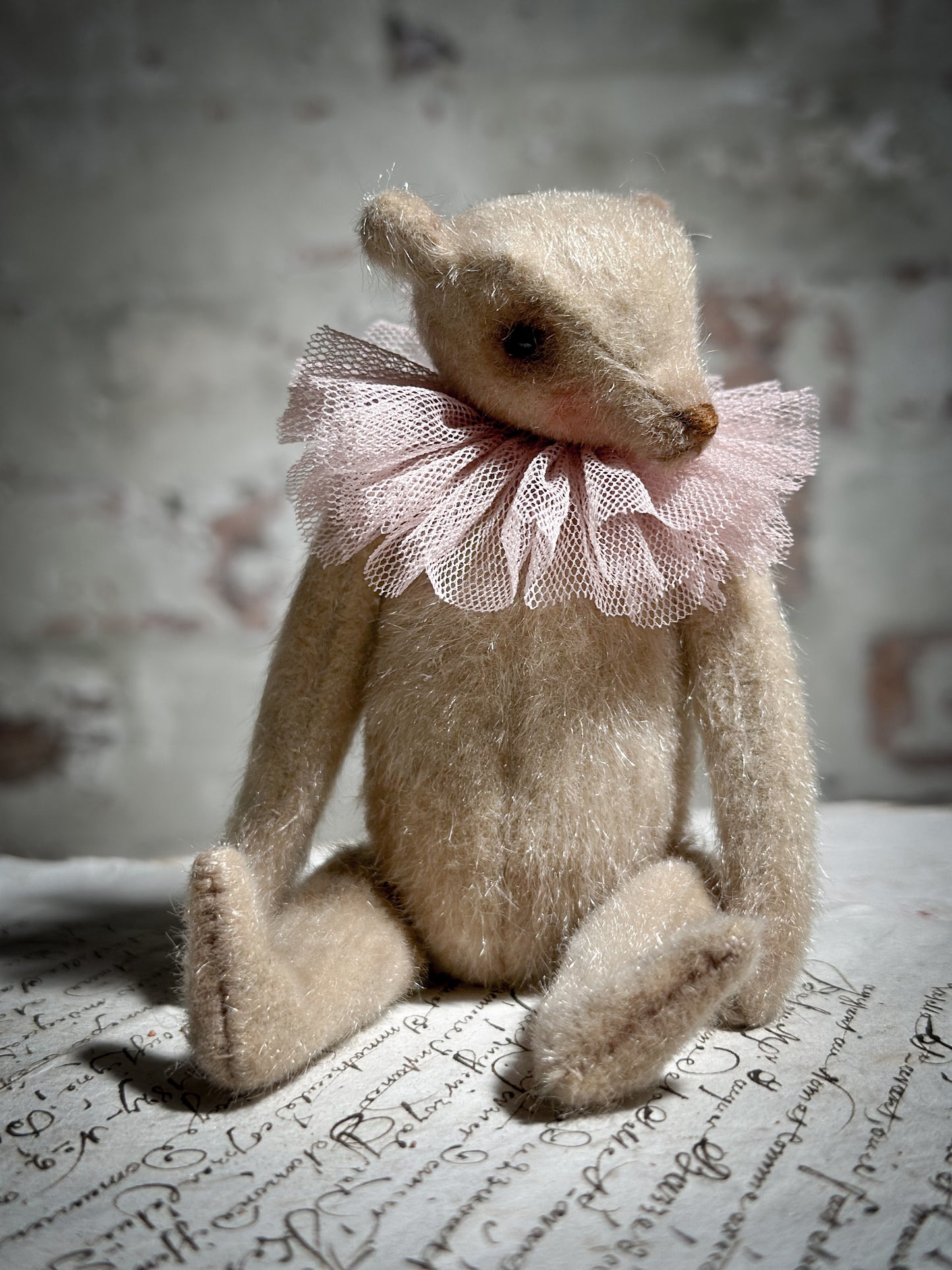 A beautiful hand made jointed collector’s teddy bear with antique pink tulle ruffle