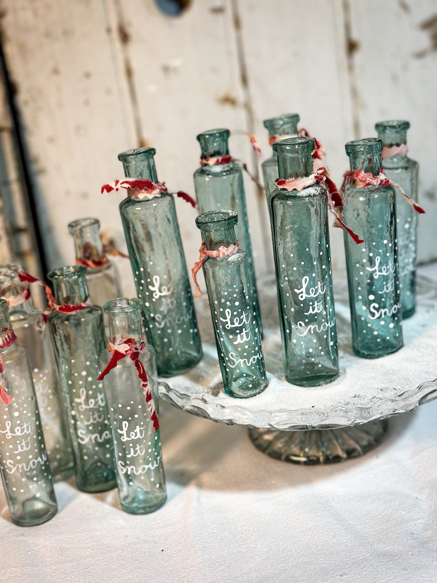 A beautiful Victorian cylinder bottle painted with a Christmas quote “Let it Snow”