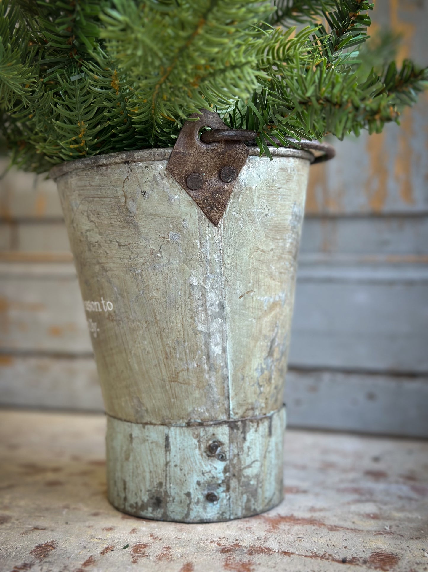 A Recycled Metal Mini Christmas Tree Bucket With A Hand Painted Quote