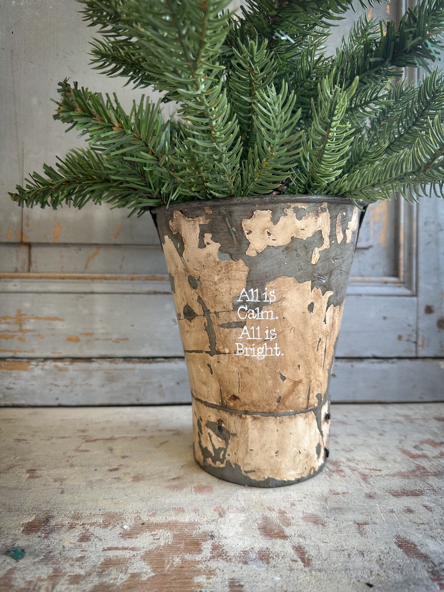 A Recycled Metal Mini Christmas Tree Bucket With A Hand Painted Quote
