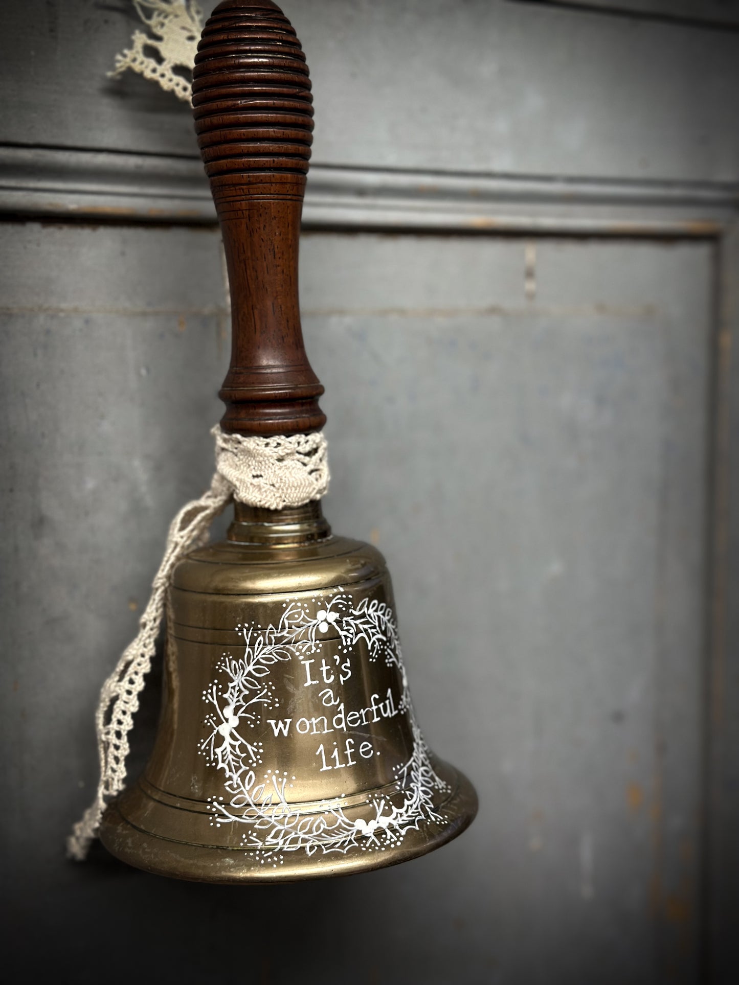 A vintage brass hand held bell with a hand painted quote