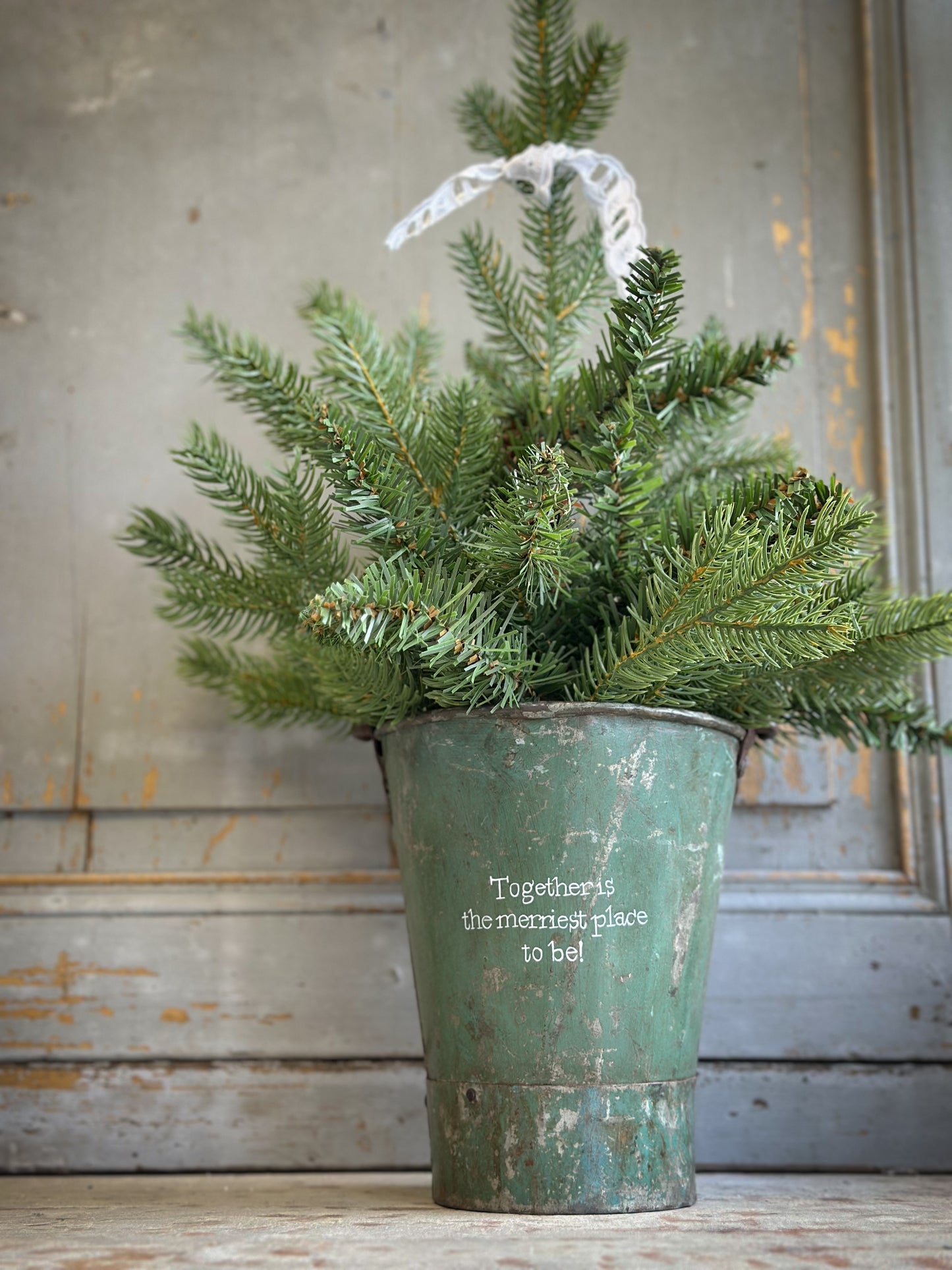 A Recycled Metal Mini Christmas Tree Bucket With A Hand Painted Quote