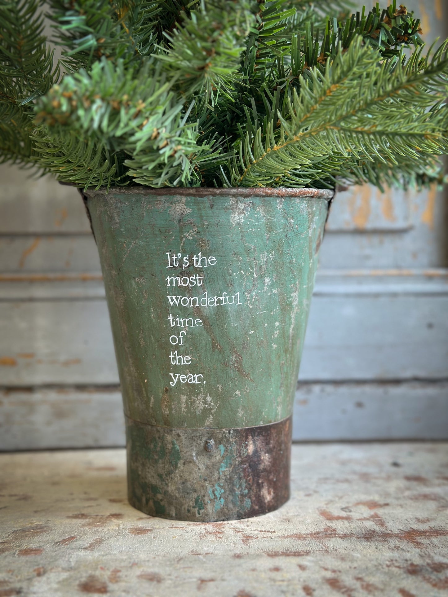 A Recycled Metal Mini Christmas Tree Bucket With A Hand Painted Quote