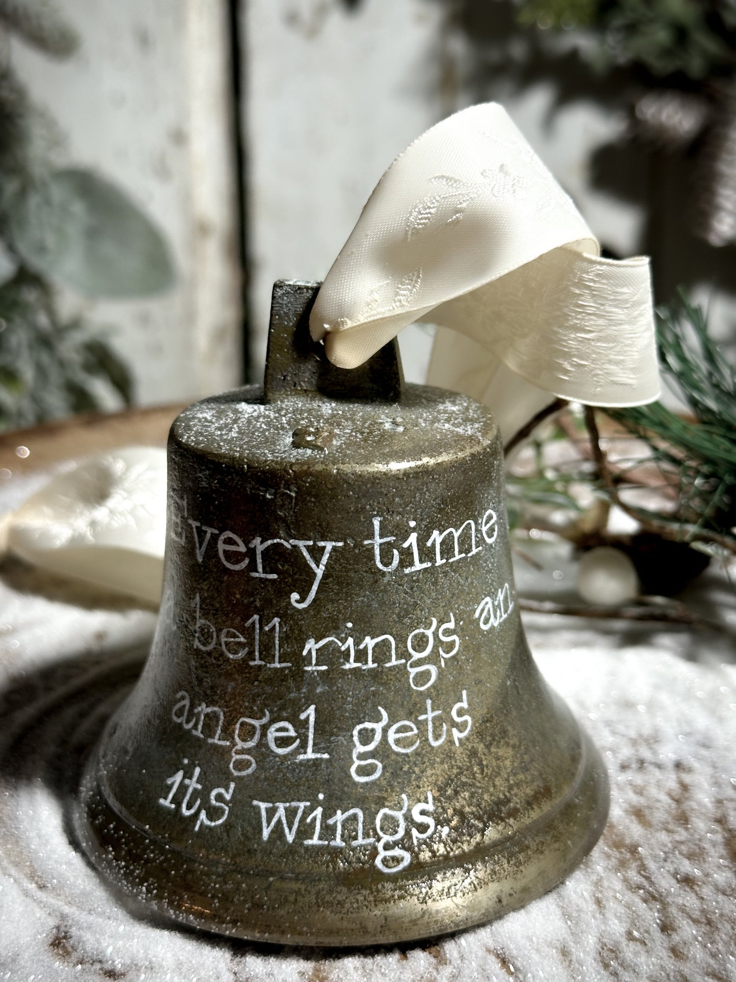 A vintage brass bell with a hand painted quote