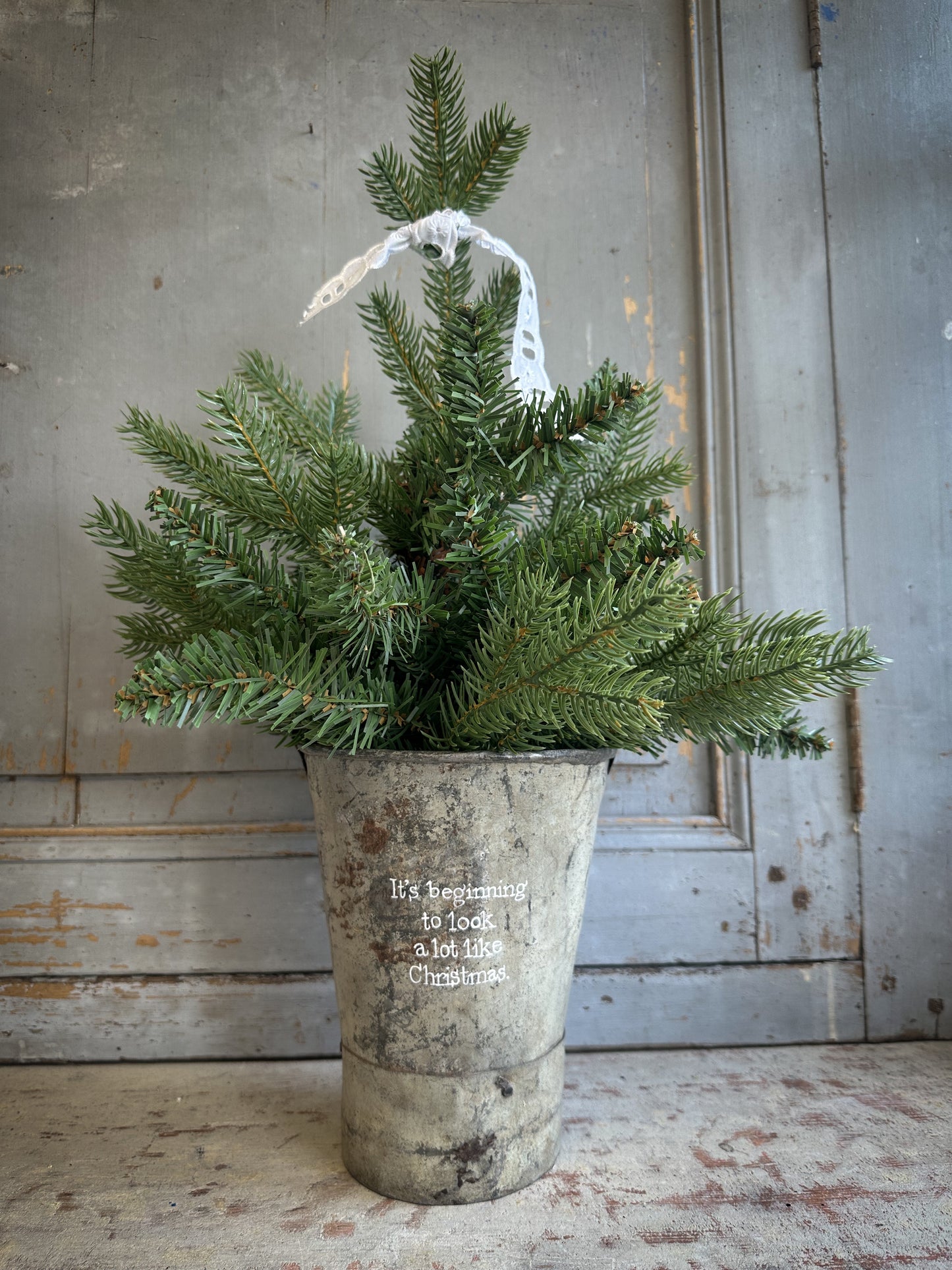 A Recycled Metal Mini Christmas Tree Bucket With A Hand Painted Quote