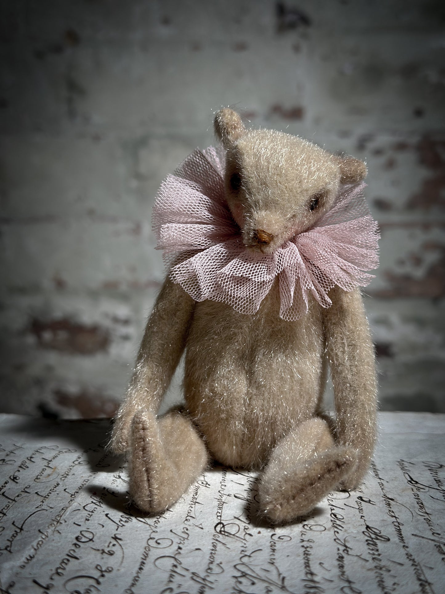 A beautiful hand made jointed collector’s teddy bear with antique pink tulle ruffle