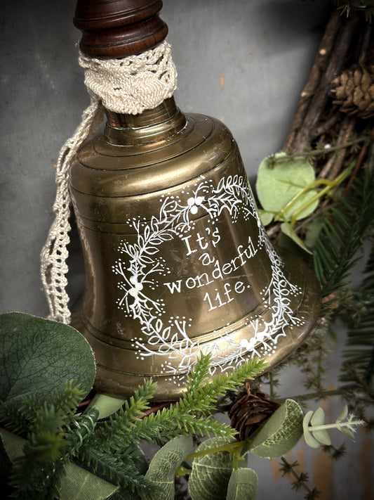 A vintage brass hand held bell with a hand painted quote