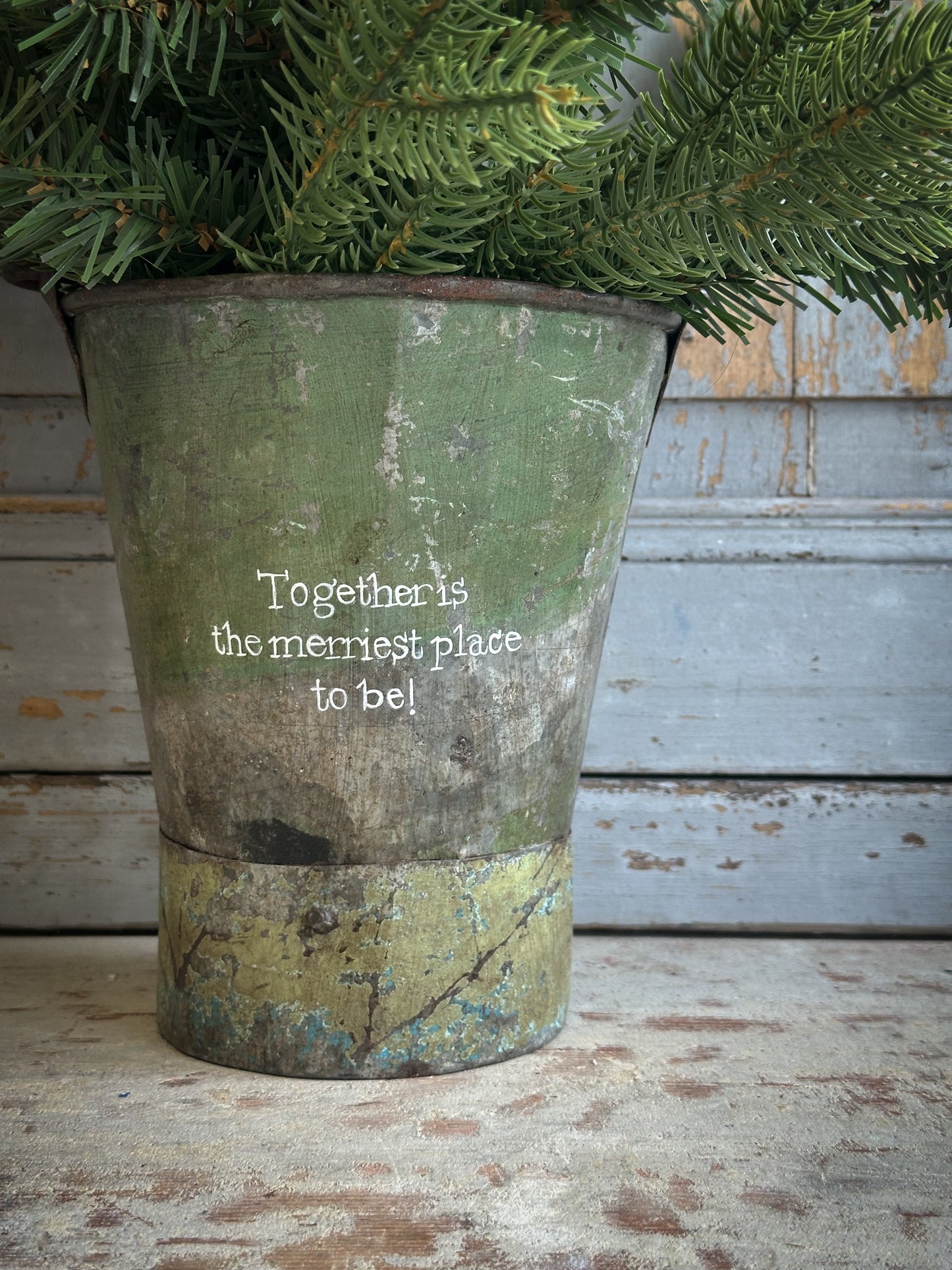 A Recycled Metal Mini Christmas Tree Bucket With A Hand Painted Quote