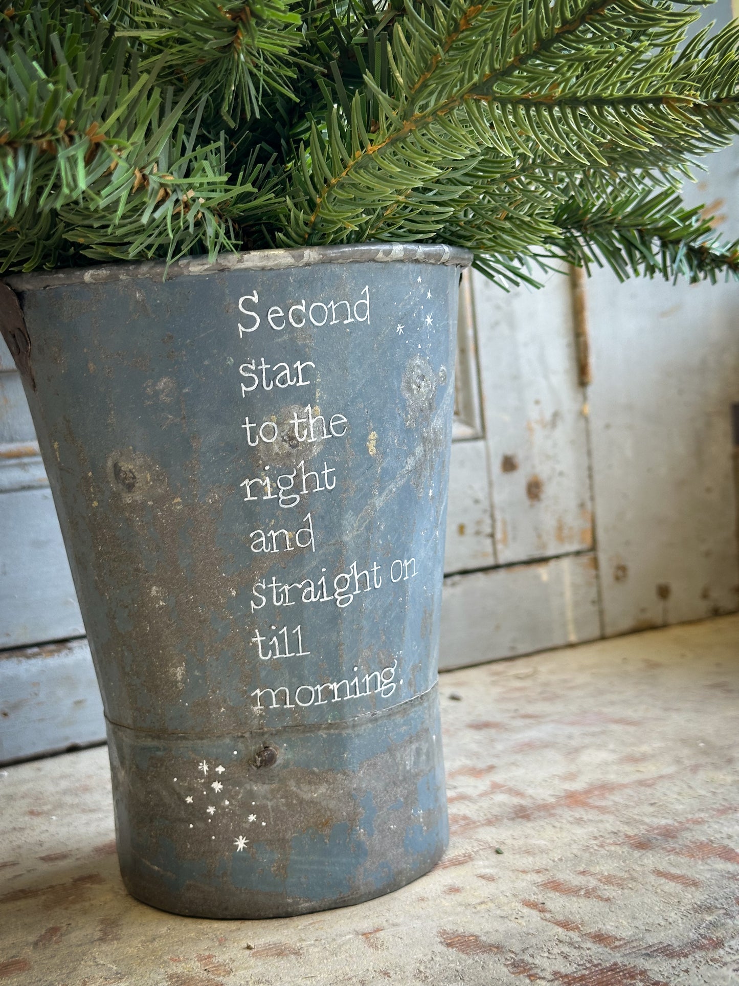 A Recycled Metal Mini Christmas Tree Bucket With A Hand Painted Quote
