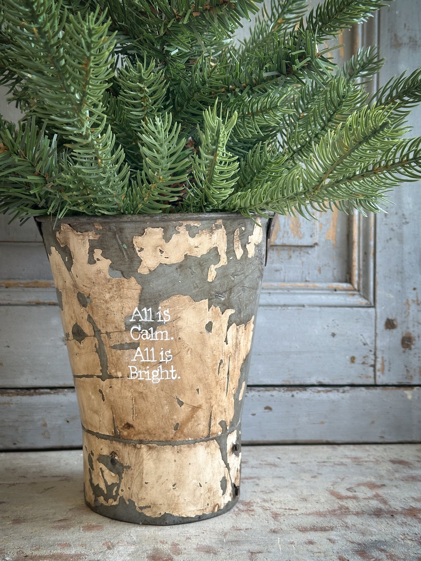 A Recycled Metal Mini Christmas Tree Bucket With A Hand Painted Quote