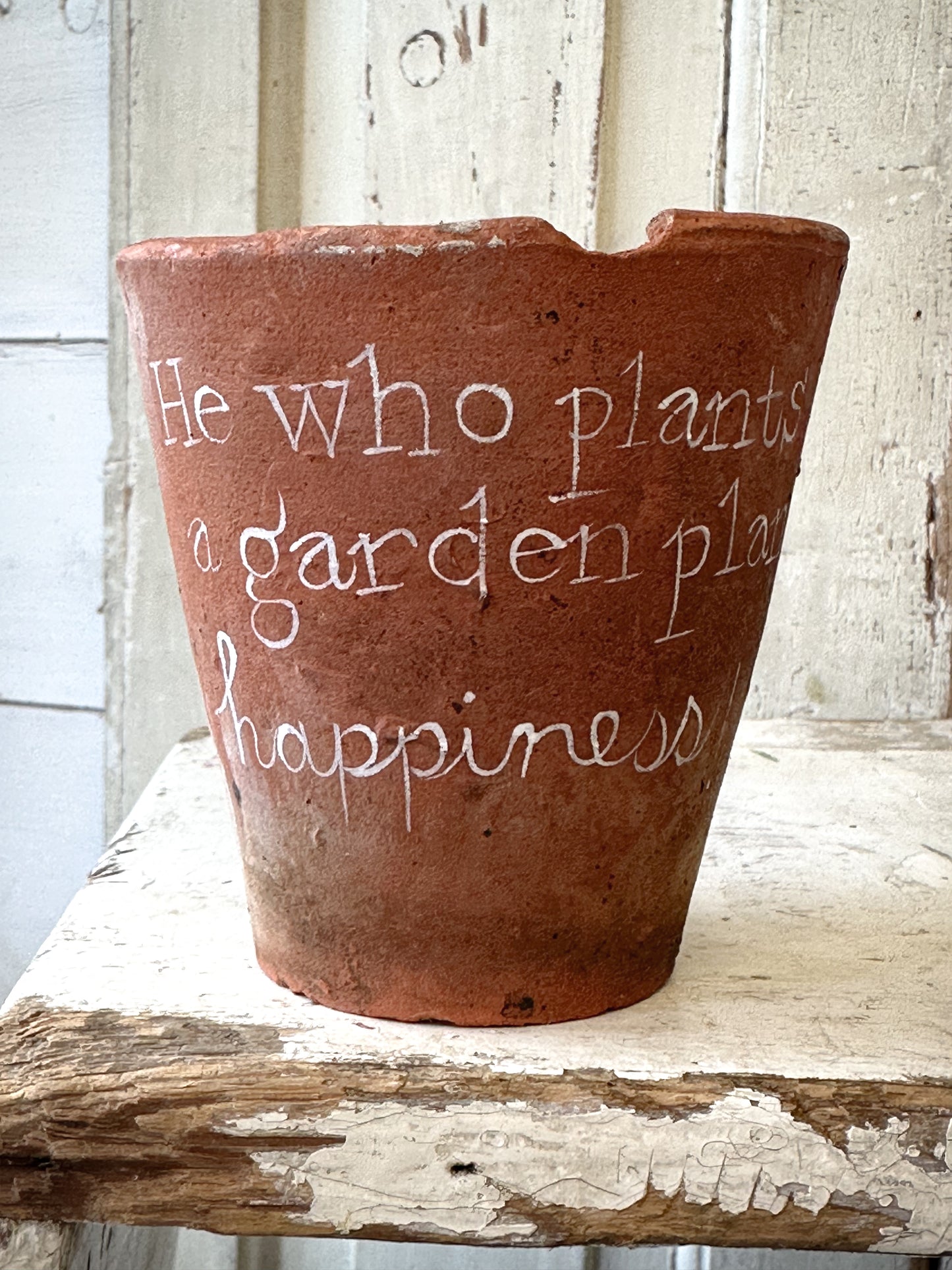 A Victorian terracotta pot with a quote “He who plants a garden”