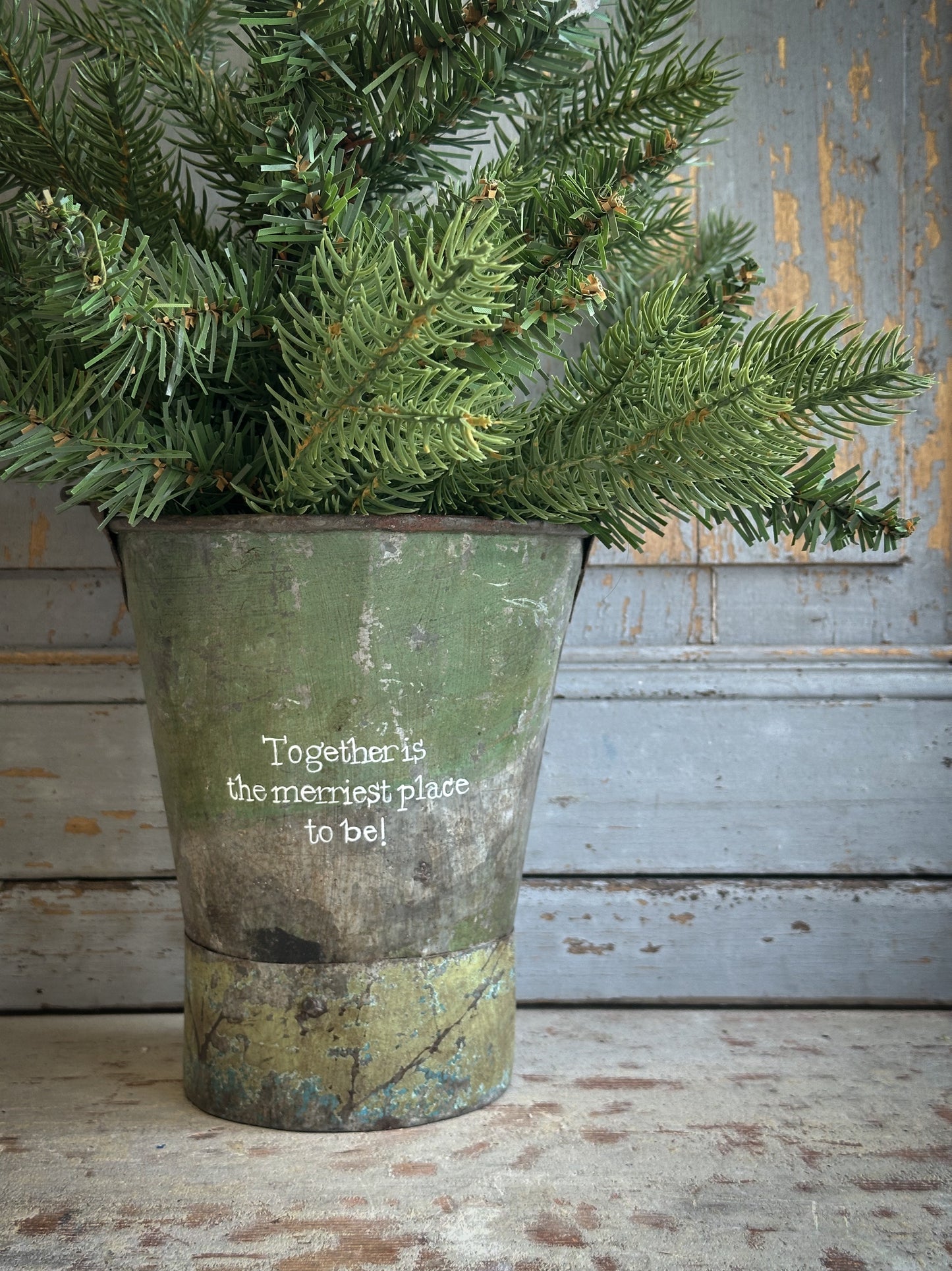 A Recycled Metal Mini Christmas Tree Bucket With A Hand Painted Quote