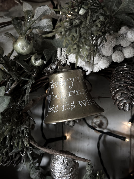 A vintage brass bell with a hand painted quote