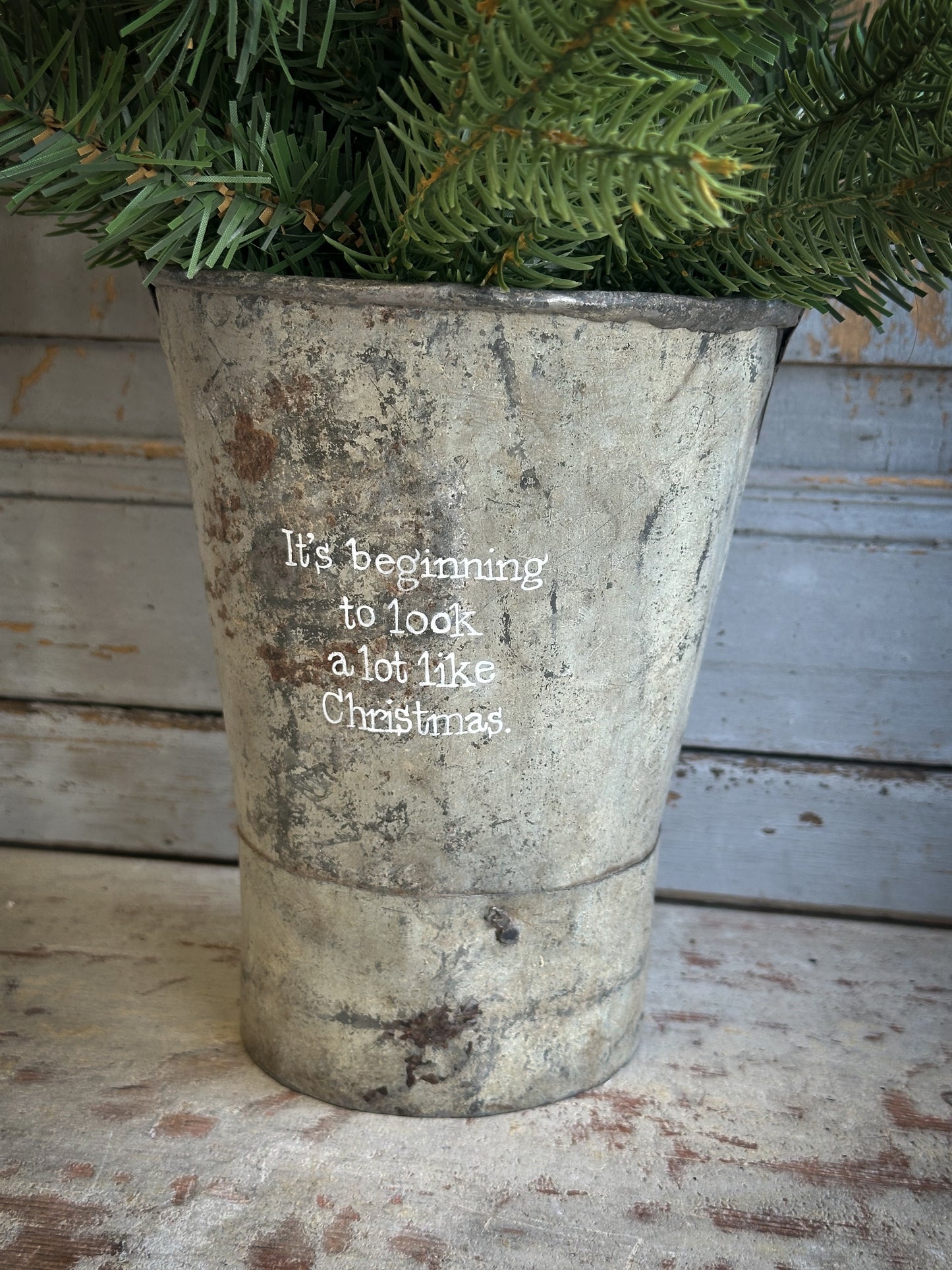 A Recycled Metal Mini Christmas Tree Bucket With A Hand Painted Quote