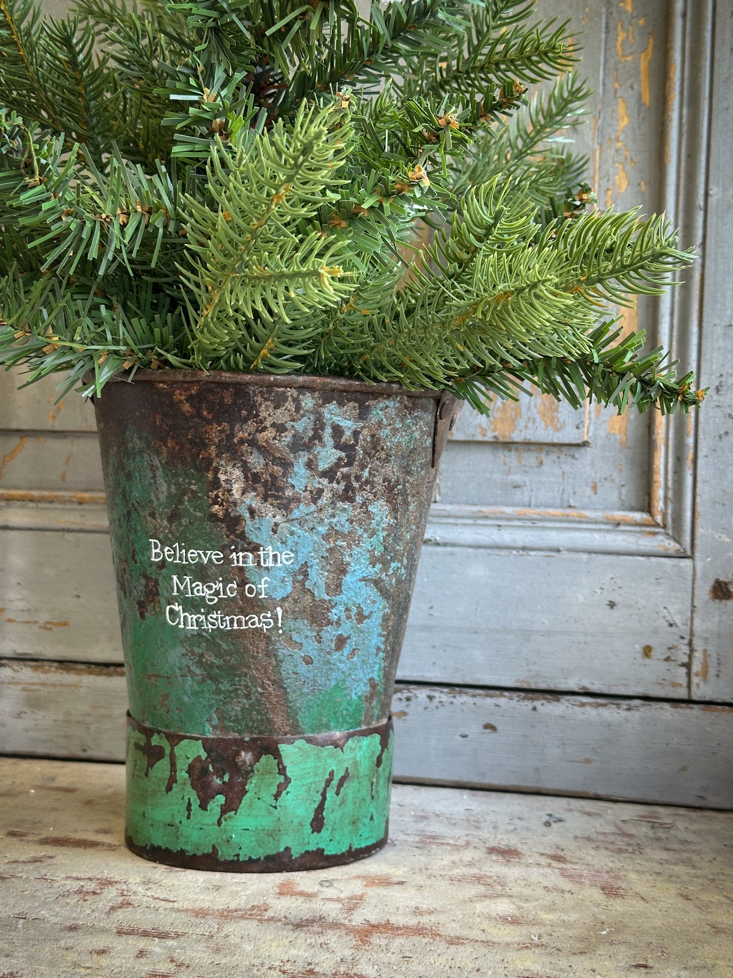 A Recycled Metal Mini Christmas Tree Bucket With A Hand Painted Quote