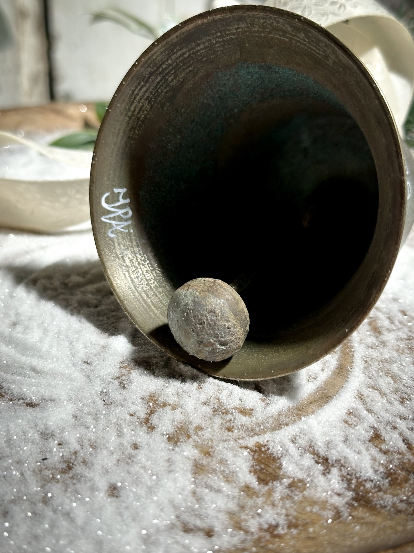 A vintage brass bell with a hand painted quote