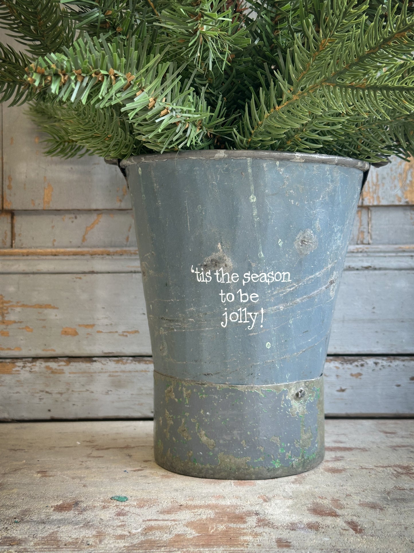 A Recycled Metal Mini Christmas Tree Bucket With A Hand Painted Quote