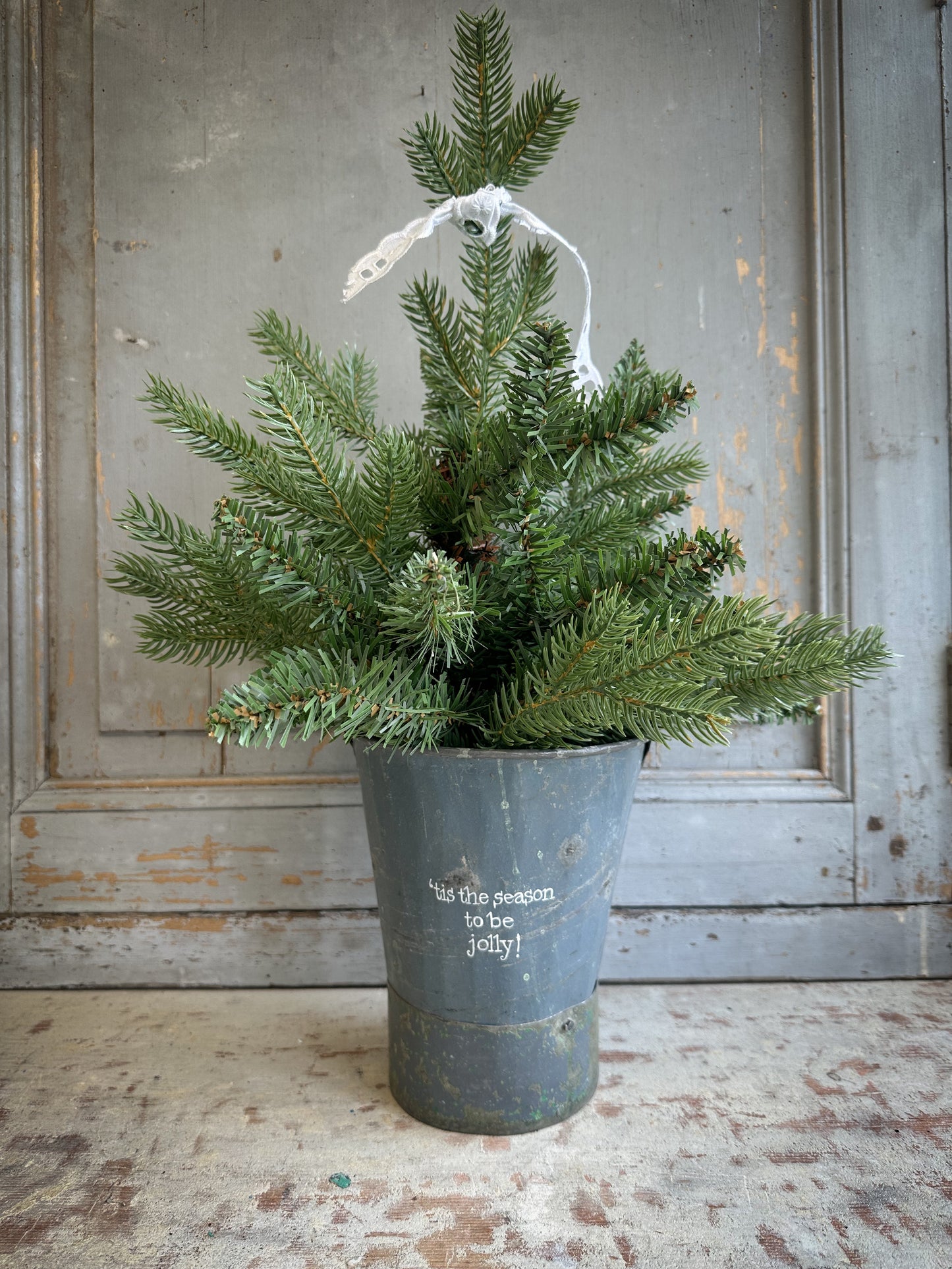 A Recycled Metal Mini Christmas Tree Bucket With A Hand Painted Quote