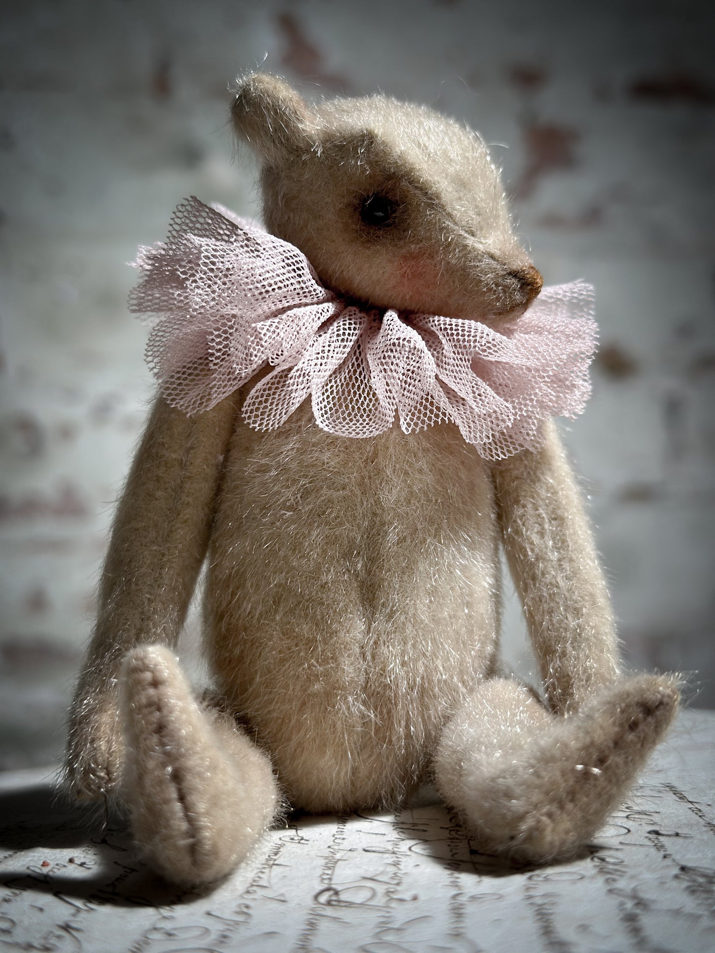 A beautiful hand made jointed collector’s teddy bear with antique pink tulle ruffle