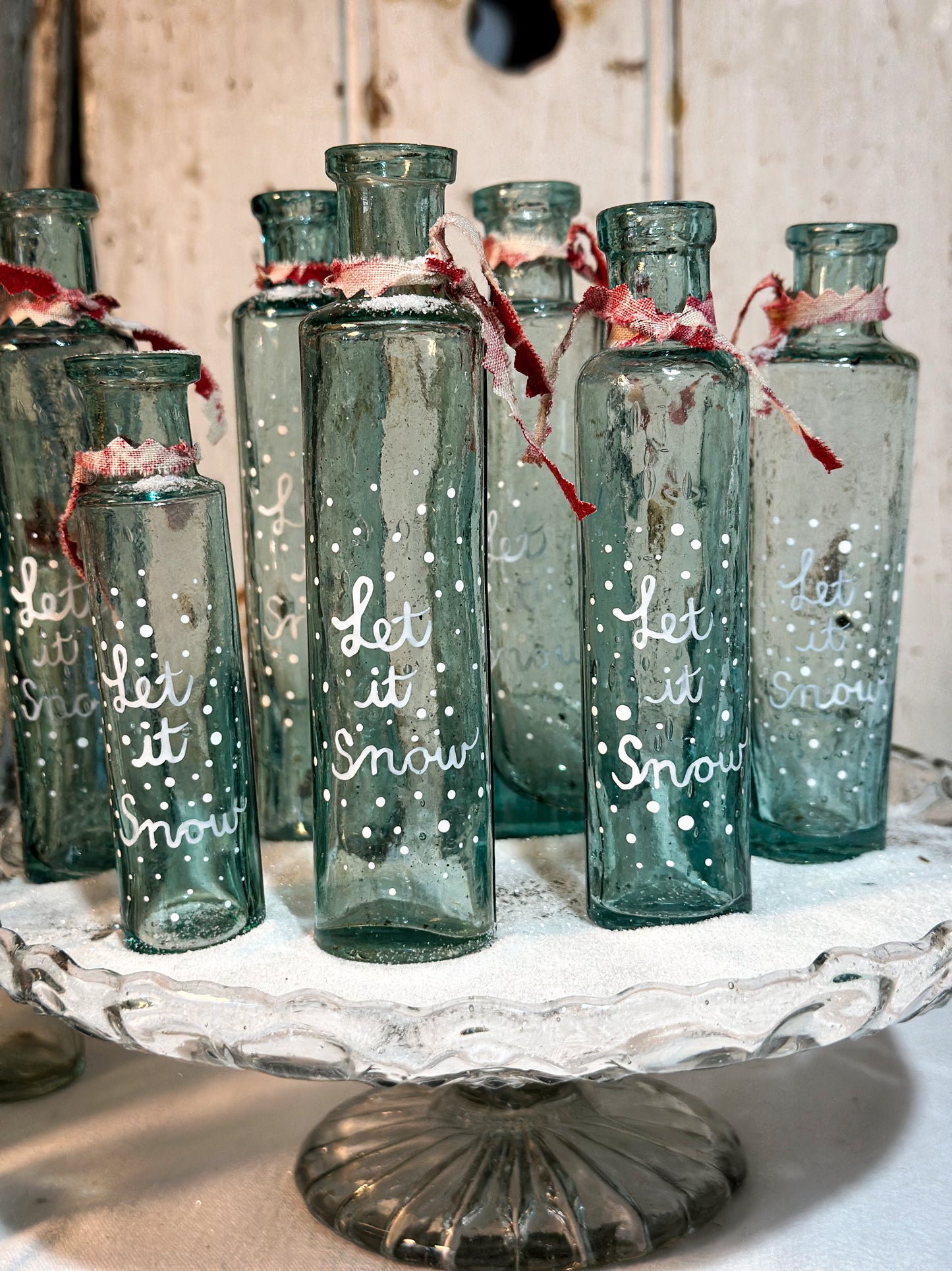 A beautiful Victorian cylinder bottle painted with a Christmas quote “Let it Snow”