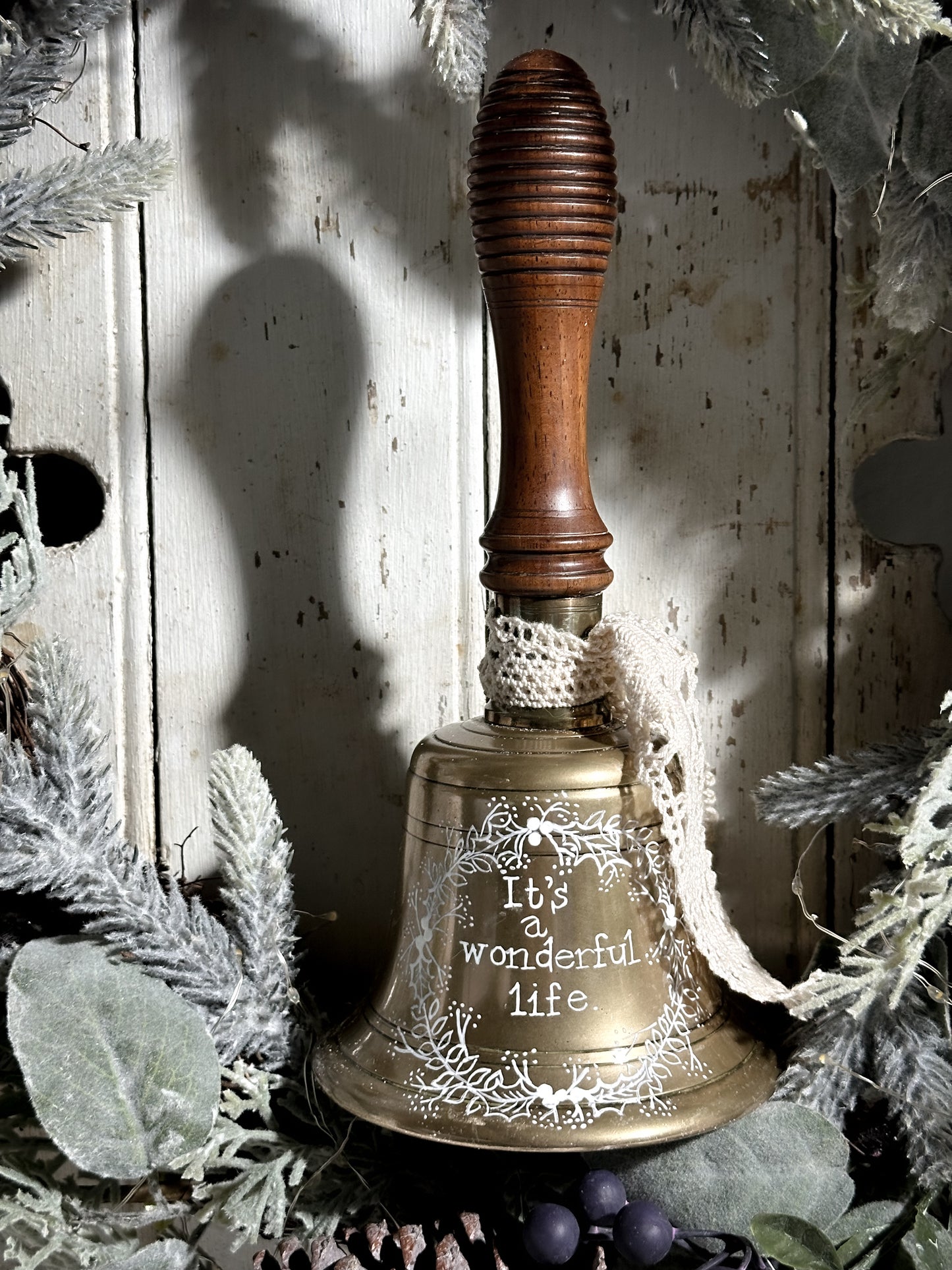 A vintage brass hand held bell with a hand painted quote