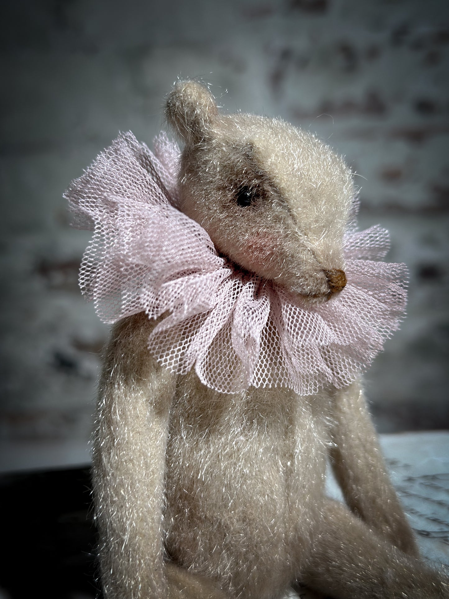 A beautiful hand made jointed collector’s teddy bear with antique pink tulle ruffle