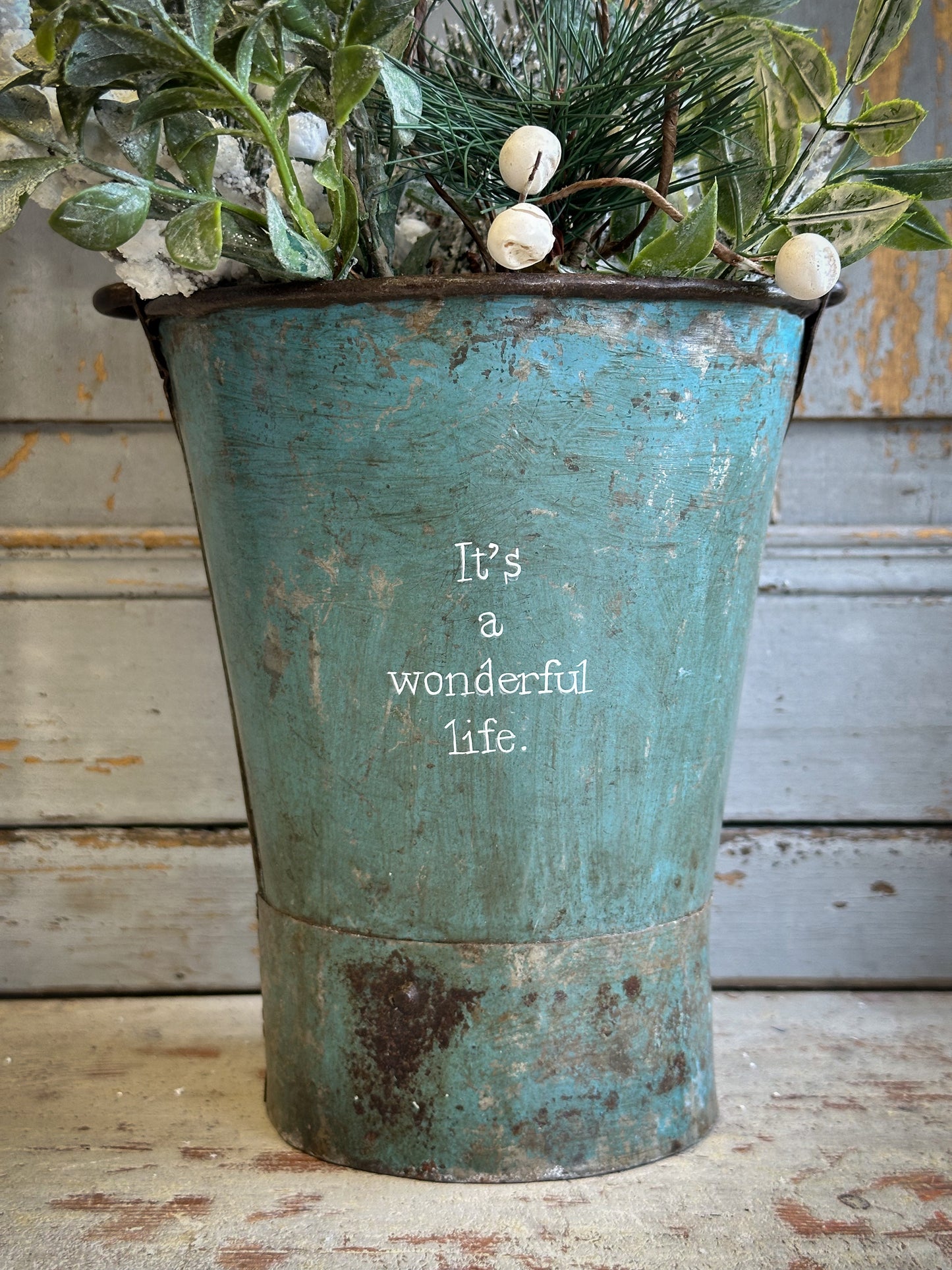 A Recycled Metal Mini Christmas Tree Bucket With A Hand Painted Quote