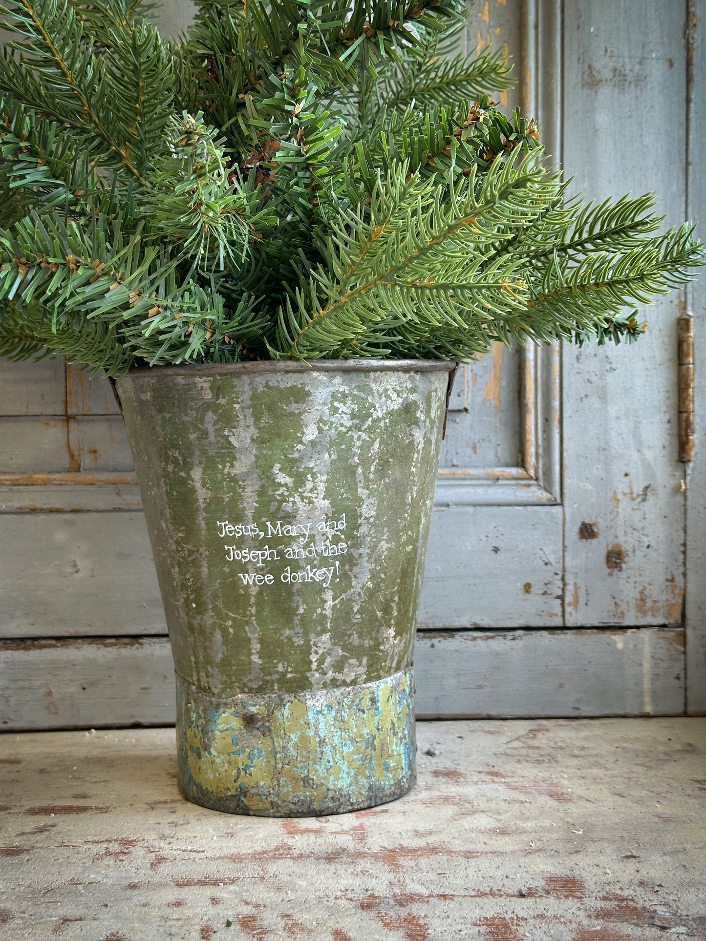 A Recycled Metal Mini Christmas Tree Bucket With A Hand Painted Quote