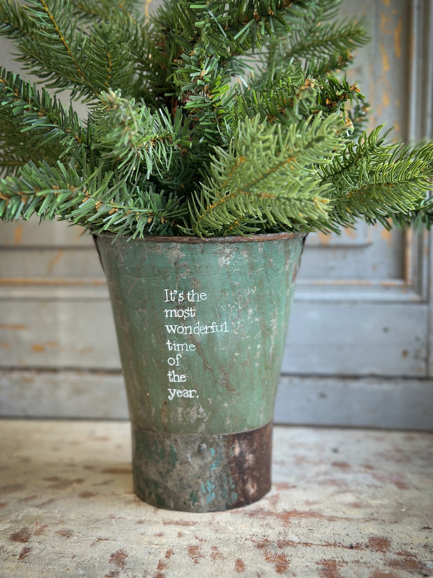 A Recycled Metal Mini Christmas Tree Bucket With A Hand Painted Quote