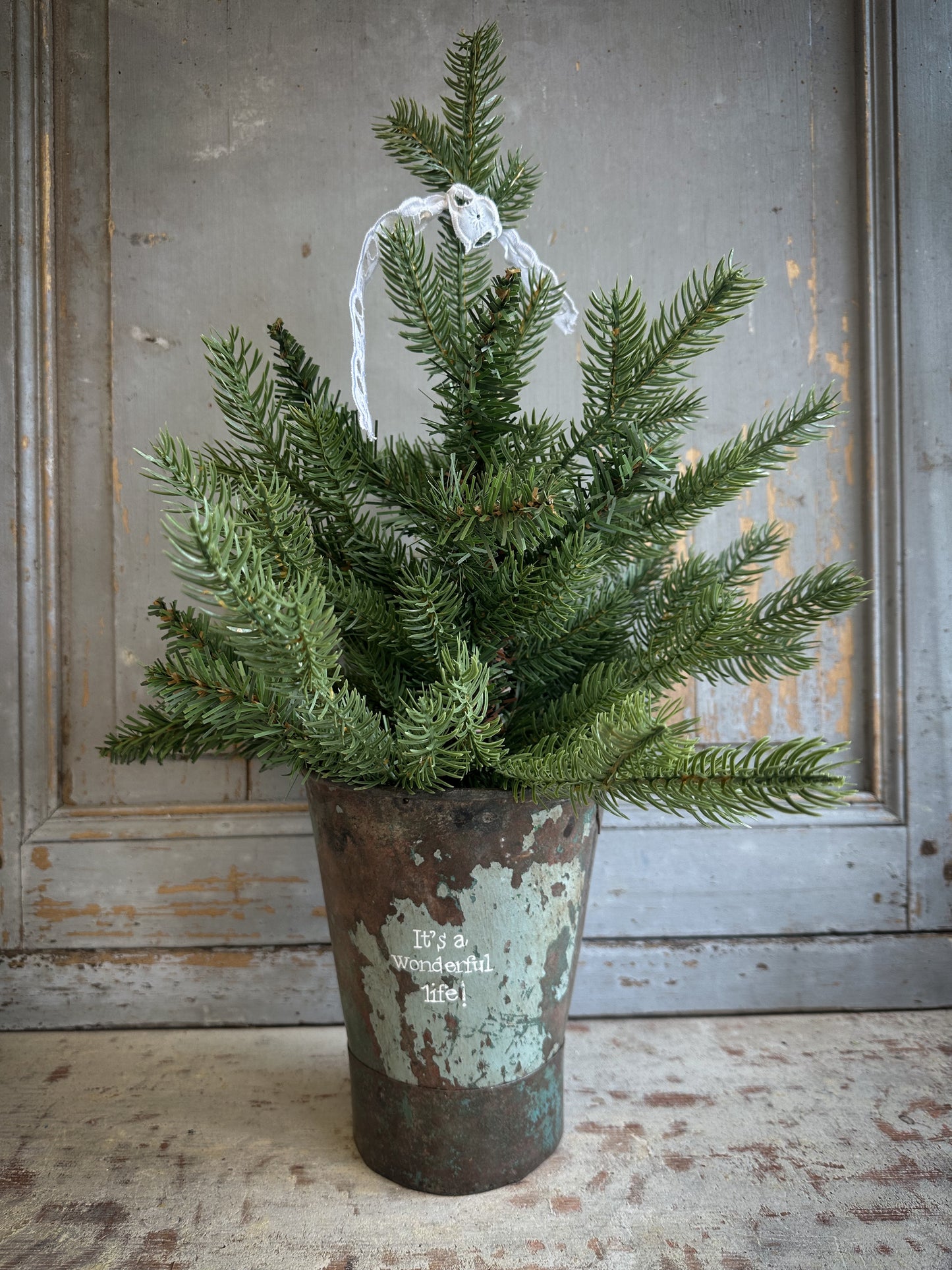 A Recycled Metal Mini Christmas Tree Bucket With A Hand Painted Quote
