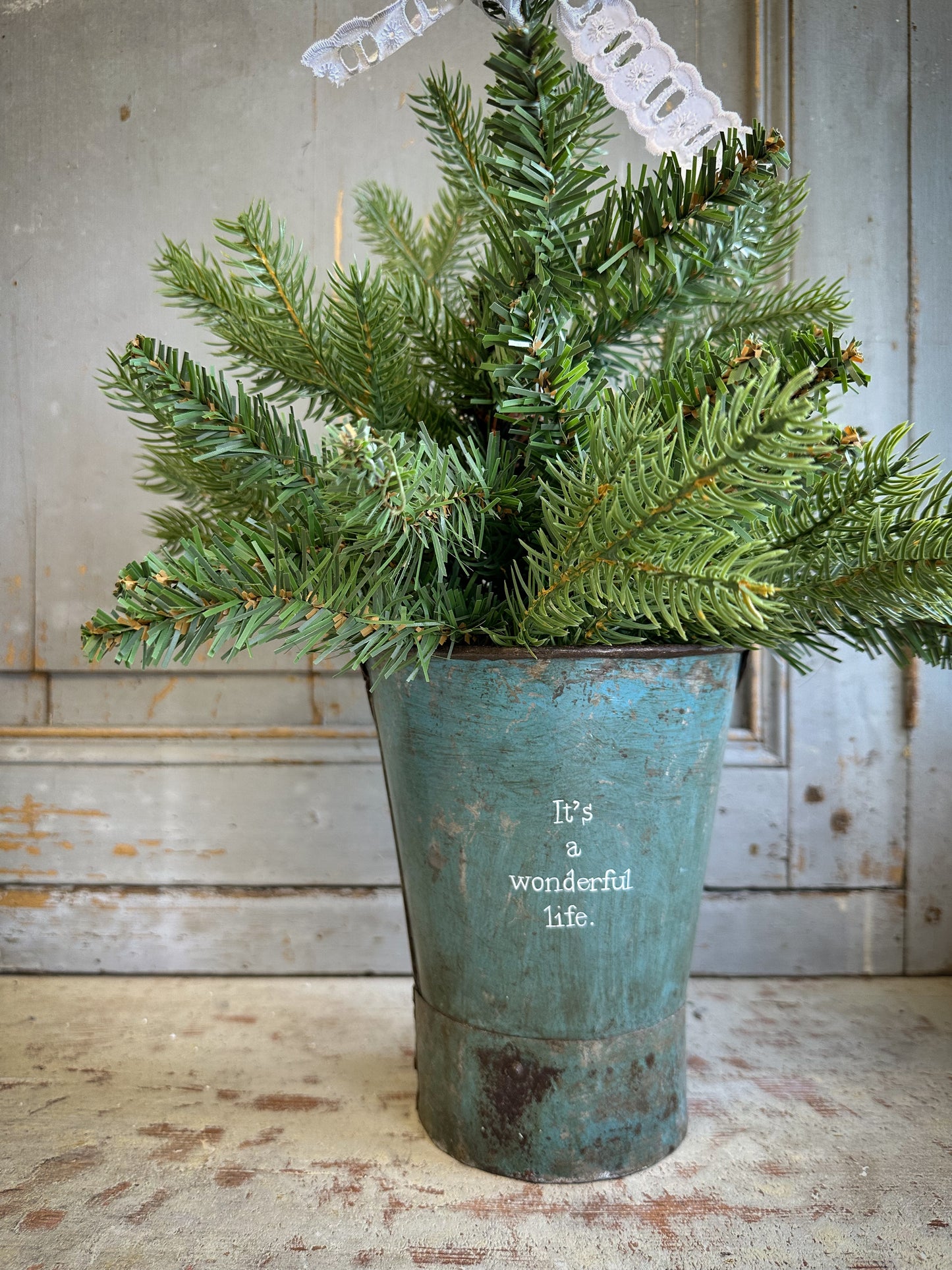 A Recycled Metal Mini Christmas Tree Bucket With A Hand Painted Quote