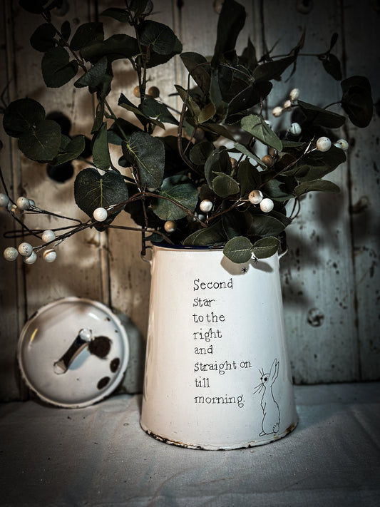 A white enamelware milk churn hand painted with a quote