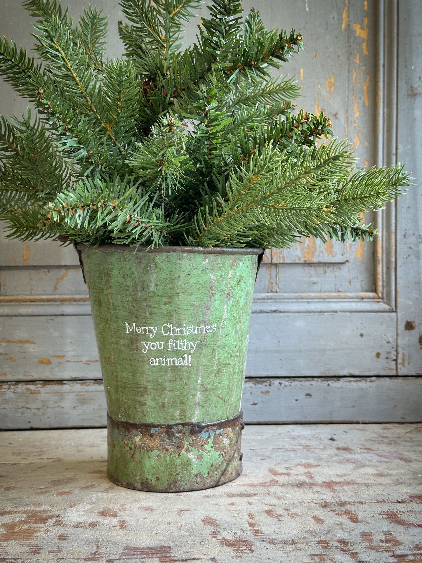 A Recycled Metal Mini Christmas Tree Bucket With A Hand Painted Quote
