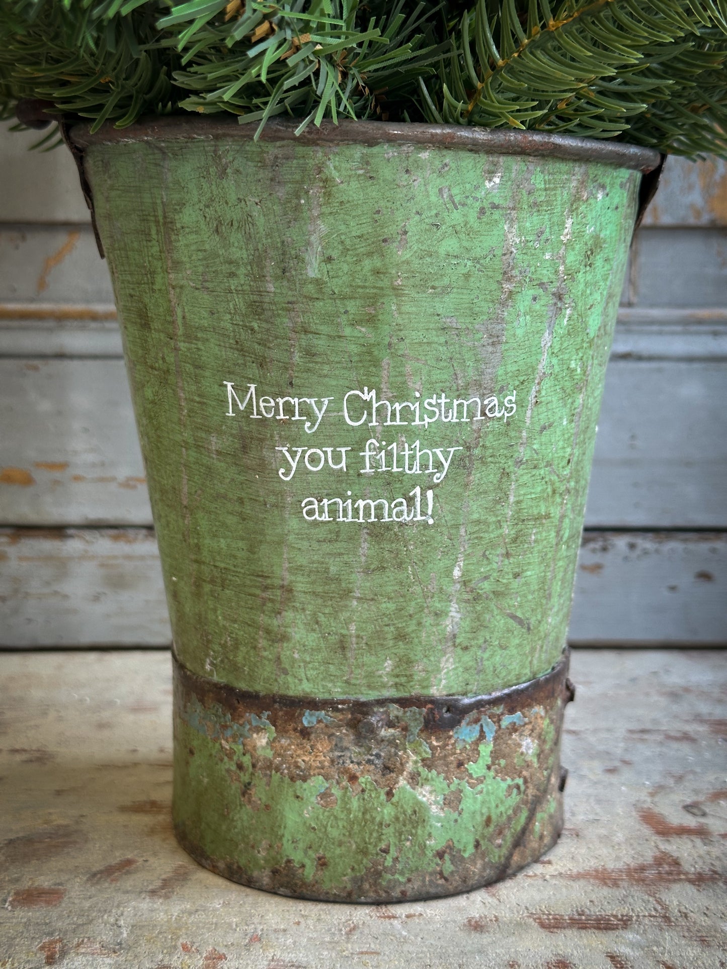 A Recycled Metal Mini Christmas Tree Bucket With A Hand Painted Quote