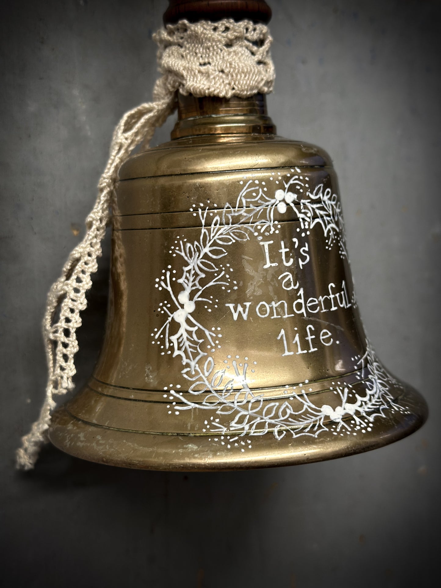A vintage brass hand held bell with a hand painted quote