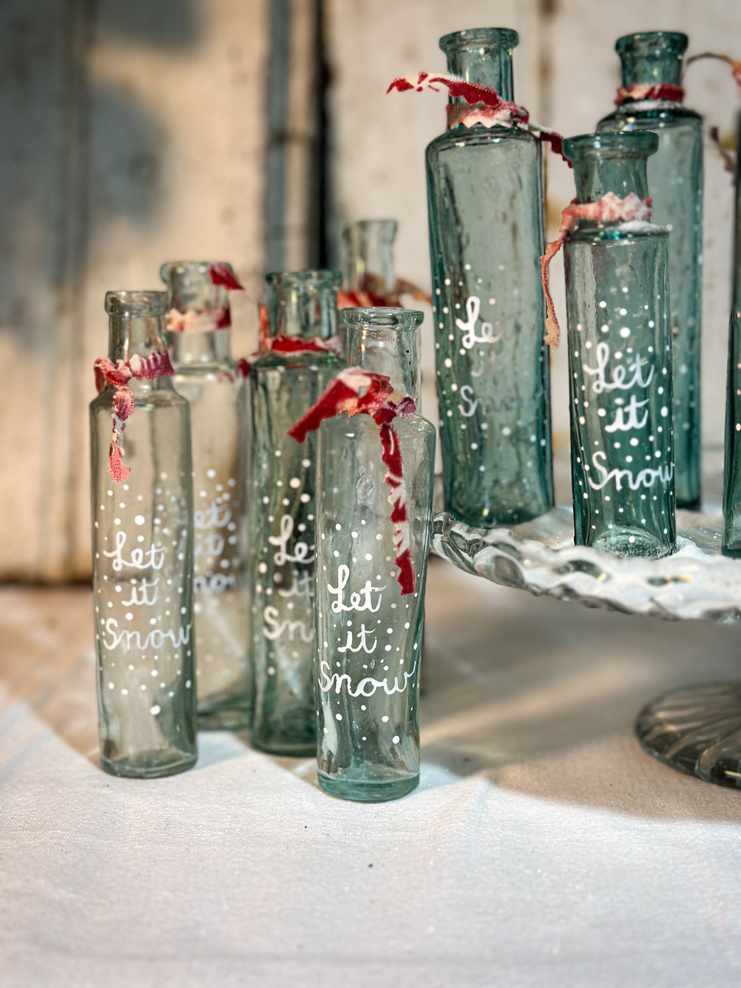 A beautiful Victorian cylinder bottle painted with a Christmas quote “Let it Snow”