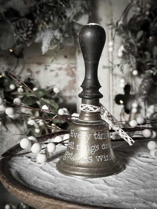 A vintage brass hand held bell with a hand painted quote