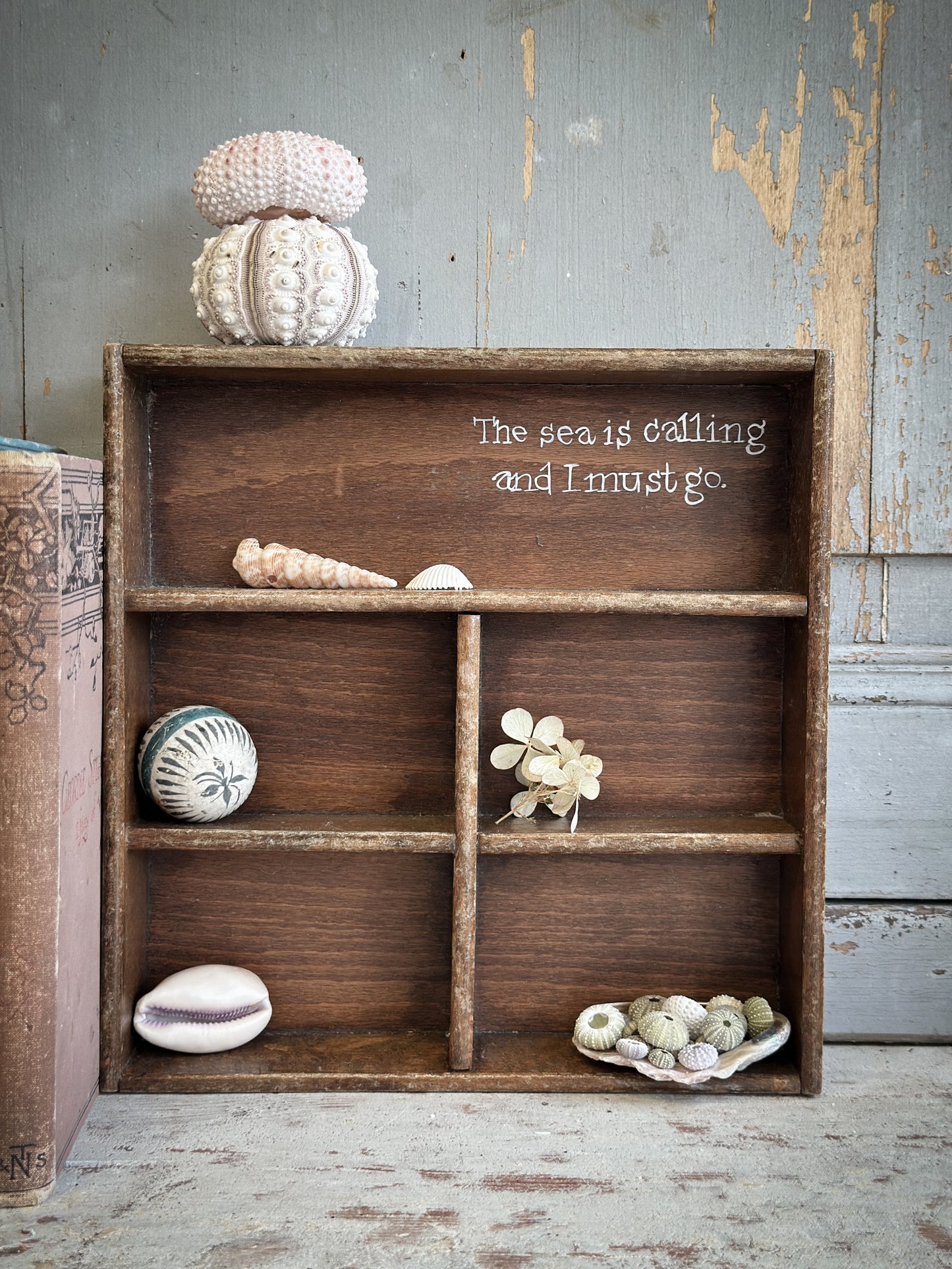 A Vintage Wooden Display Shelf With Hand Painted Quote