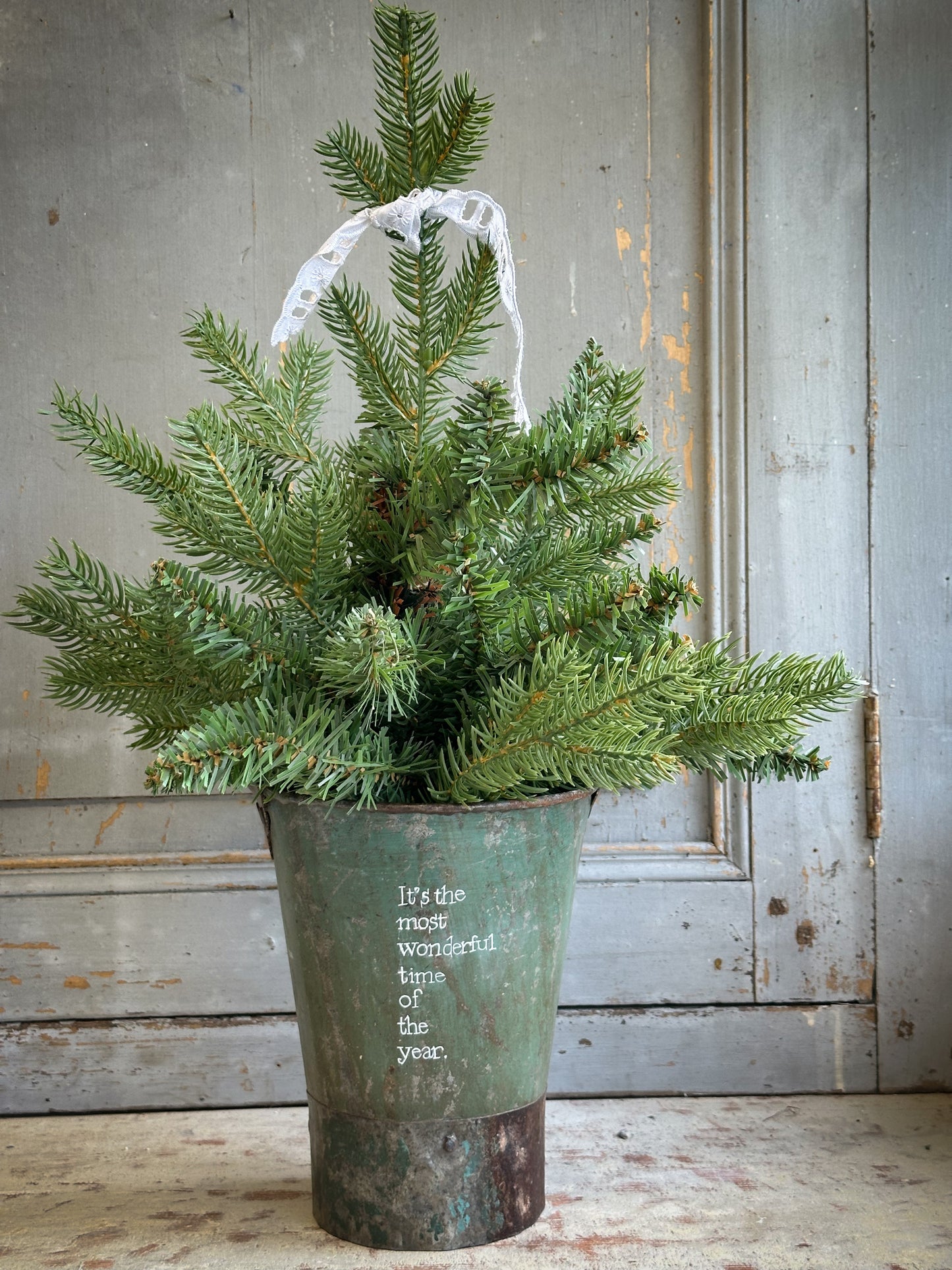 A Recycled Metal Mini Christmas Tree Bucket With A Hand Painted Quote